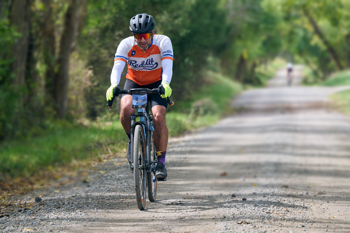 Cyclist riding a tree-lined gravel road